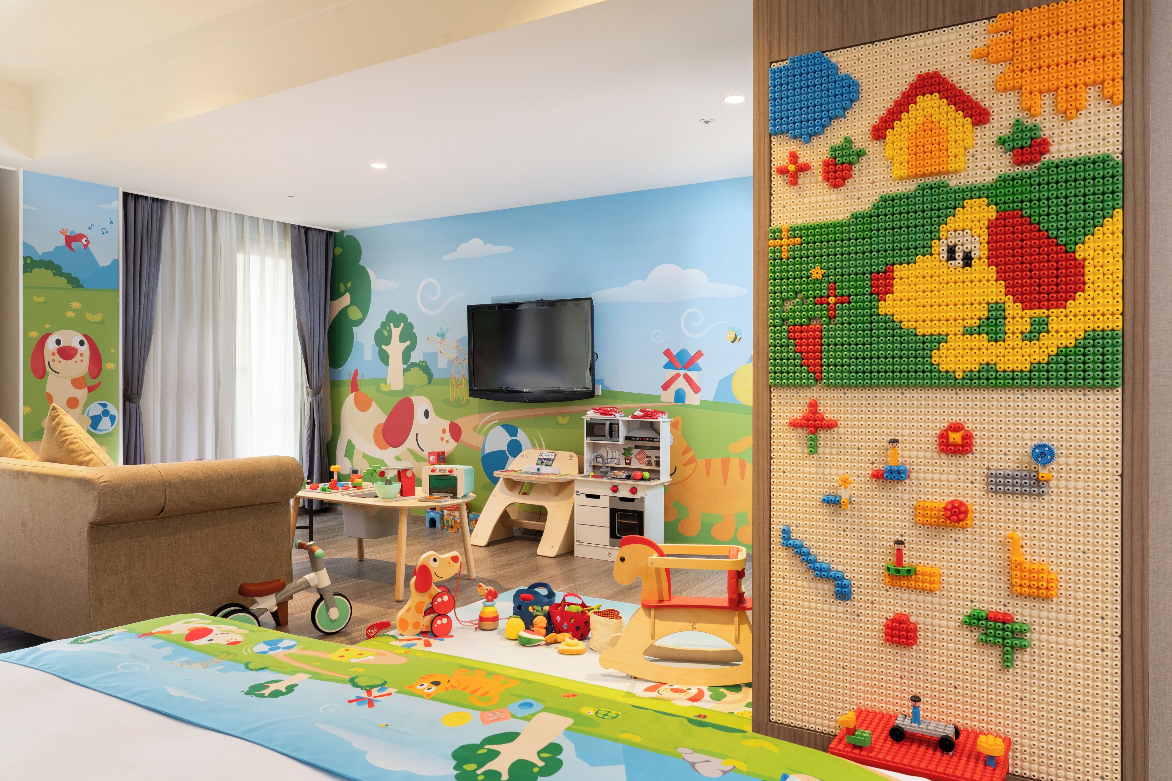 Quarto ideal para crianças, com espaço de recreação, sofá e televisão.