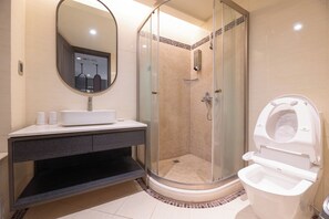 Un baño moderno con ducha de vidrio, lavamanos blanco y un inodoro.