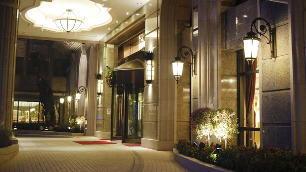 Entrada de hotel con un arco imponente, alfombra roja e interior bien iluminado.