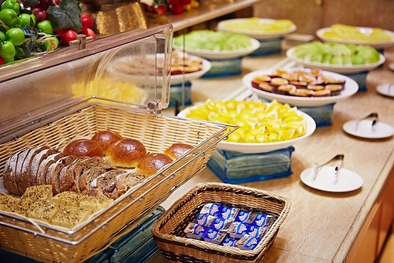 A buffet with various food items including bread, pastries, and fruits.