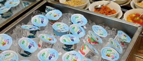 Un bufé con diversos alimentos y recipientes de yogur sobre hielo.