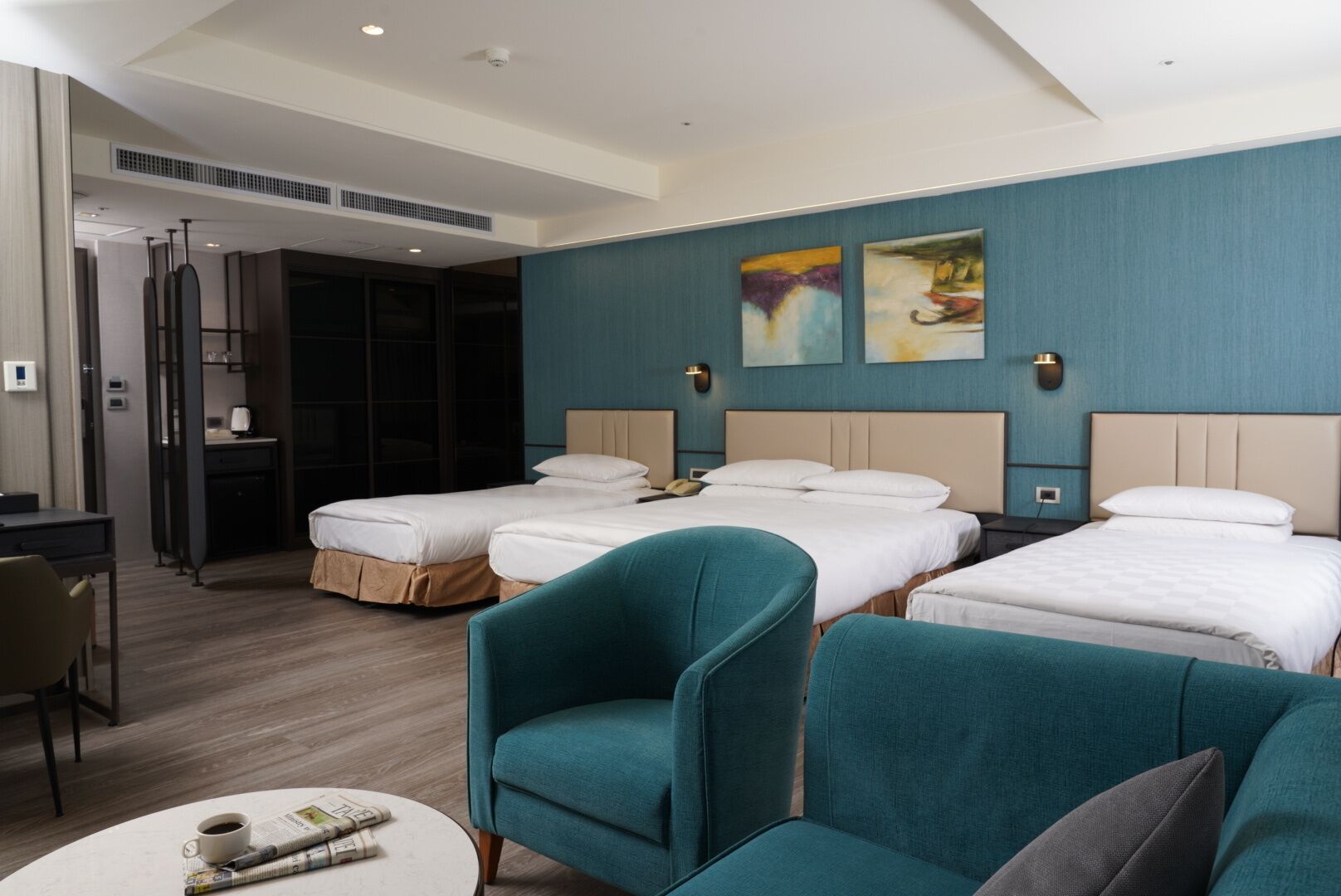 A hotel room with two beds, a desk, and a seating area with chairs.