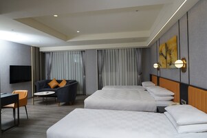 Una camera d'albergo con un letto grande, una poltrona, una scrivania e un televisore.