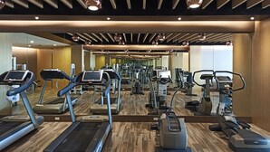 Un gimnasio con cintas de correr, elípticas y otros equipos de cardio.