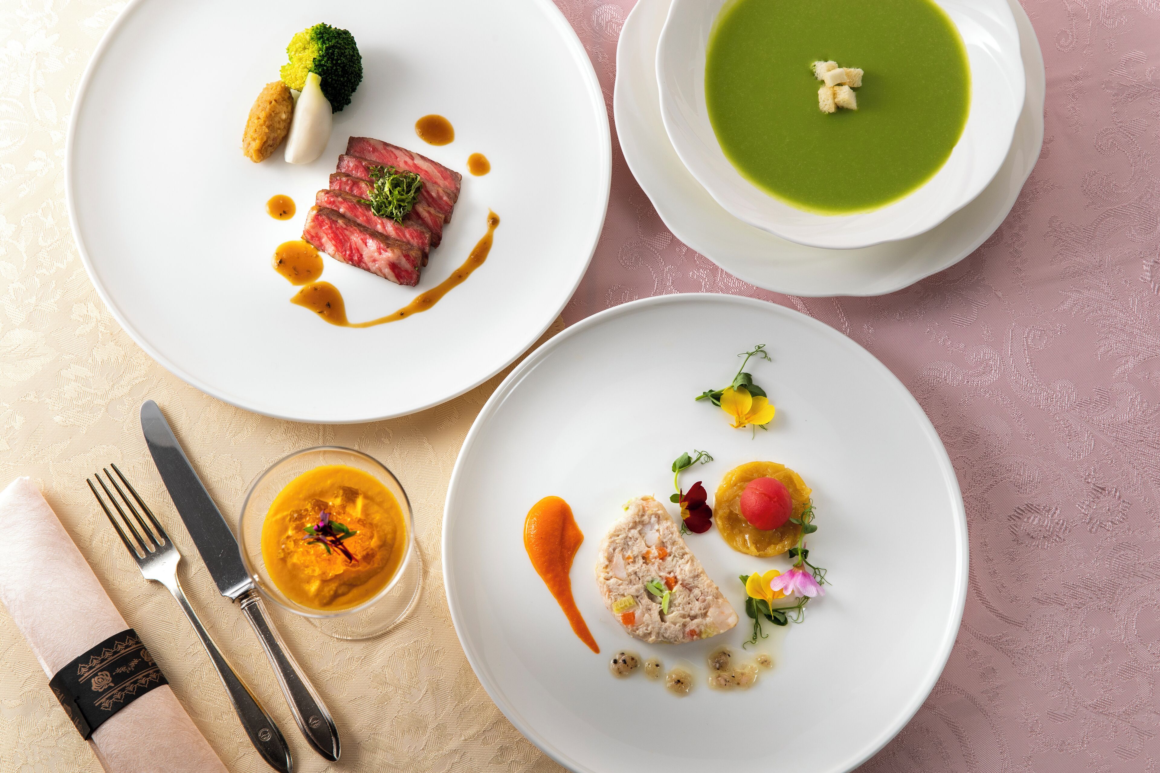 A table with plates of food, a knife, and a fork.