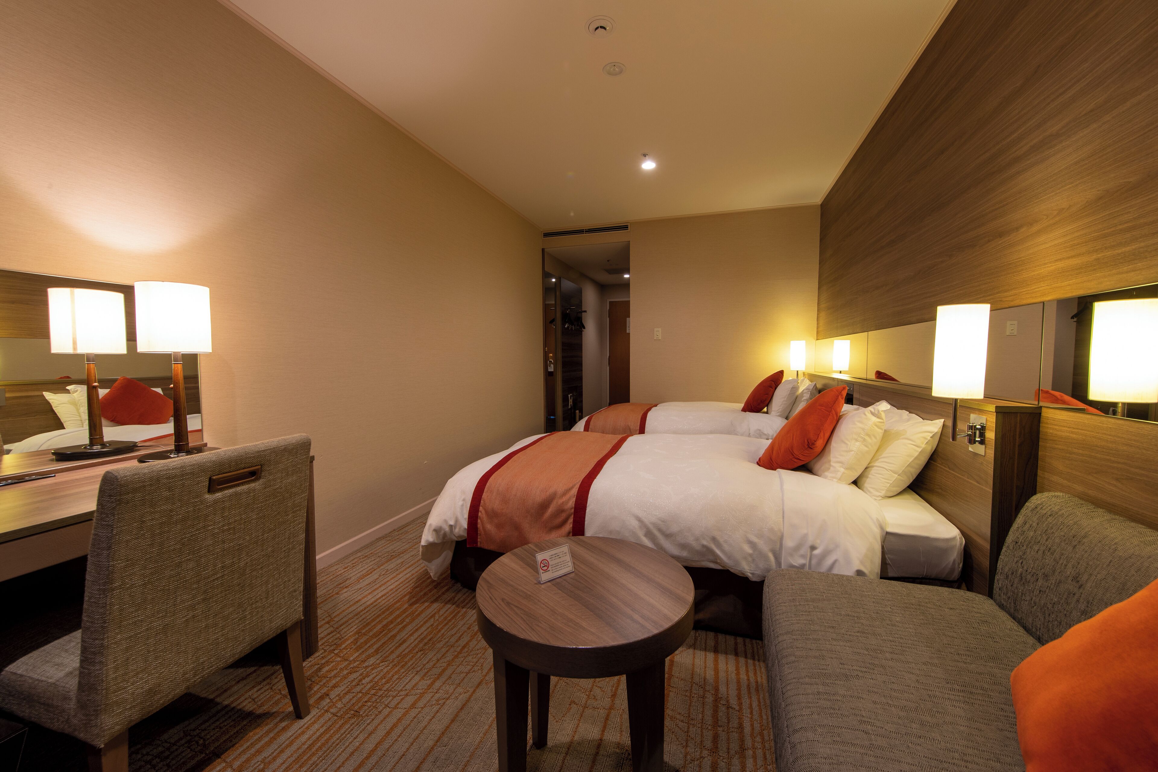 A hotel room with a bed, a desk, a chair, and a small table.