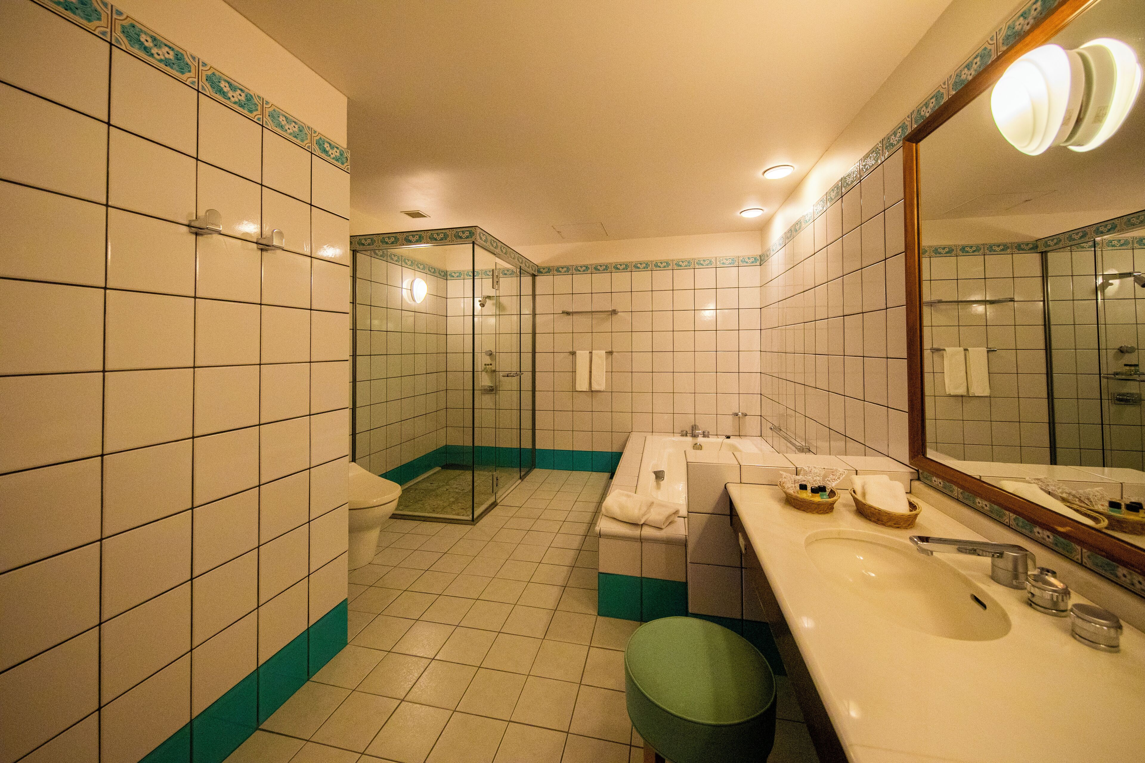 Une salle de bain dotée d’un grand lavabo, d’une douche à parois de verre et d’un miroir avec éclairage intégré.