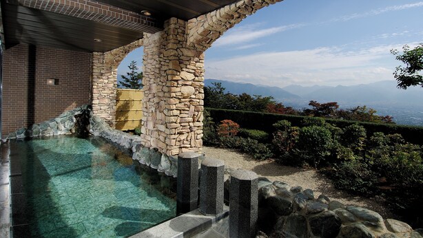 A stone archway leading to a clear pool with a view of mountains. - Fruit Park Fujiya Hotel (Yamanashi)