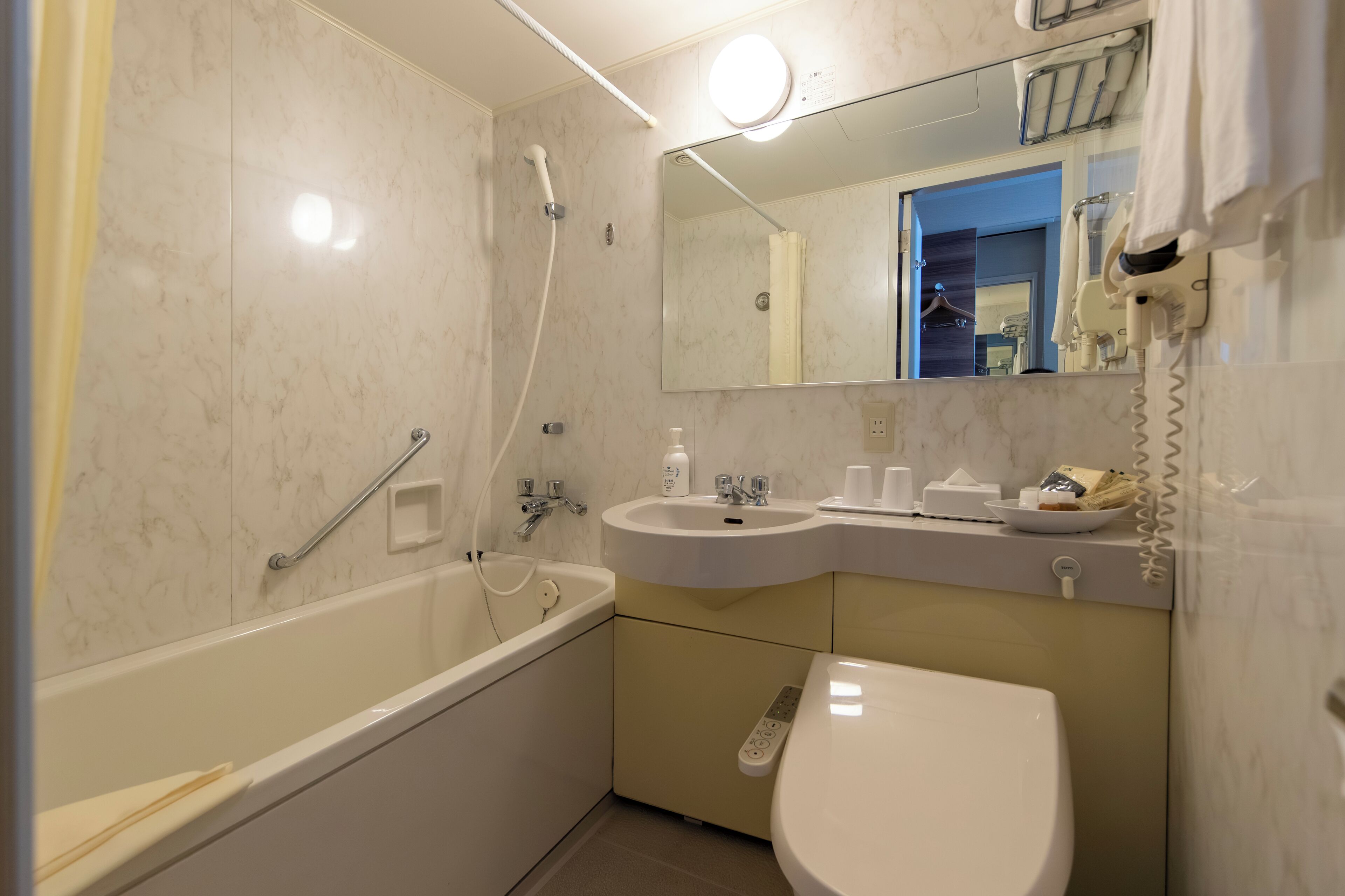 A modern bathroom with a bathtub, a sink, a toilet, and a mirror.