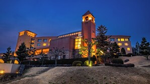 A large, multi-story building with a prominent tower and a well-lit entrance. - Fruit Park Fujiya Hotel (Yamanashi)
