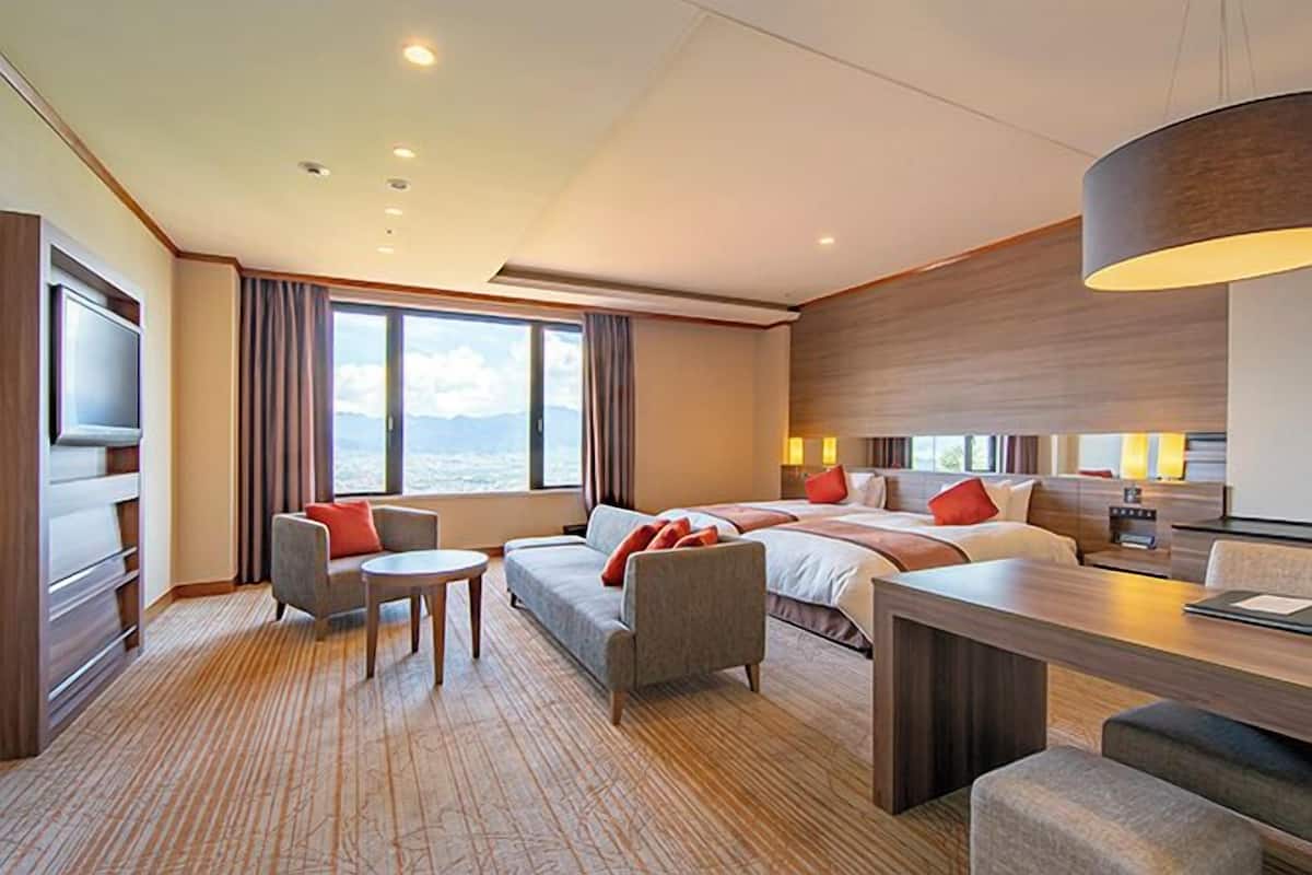 Ein modernes Hotelzimmer mit einem großen Bett, einer Couch, einem Schreibtisch und einem Fernseher.