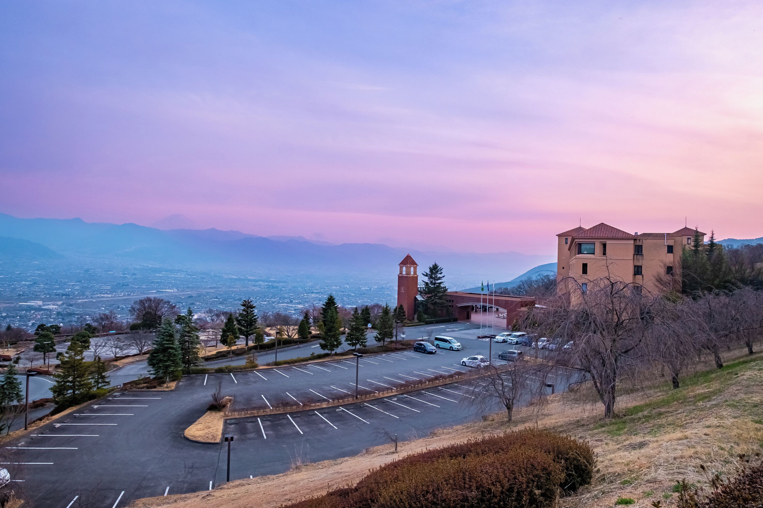 A parking lot with a building and a tower in the background.