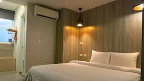 A modern bedroom with a large bed, wooden panel walls, a ceiling light, and an air conditioning unit. - S&E Hotel (Tainan)