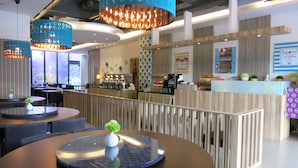 A modern restaurant with round tables, blue hanging lights, and a counter with a wooden finish. - S&E Hotel (Tainan)