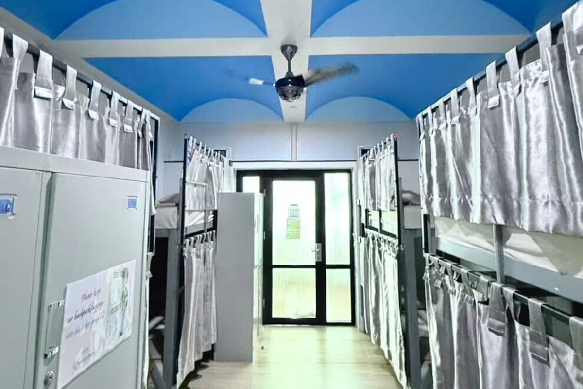 Ein Korridor mit Stockbetten, einem Deckenventilator und einer Tür am Ende.