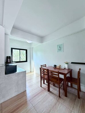 A modern kitchen with a dining area, a large window, and a small artwork on the wall.