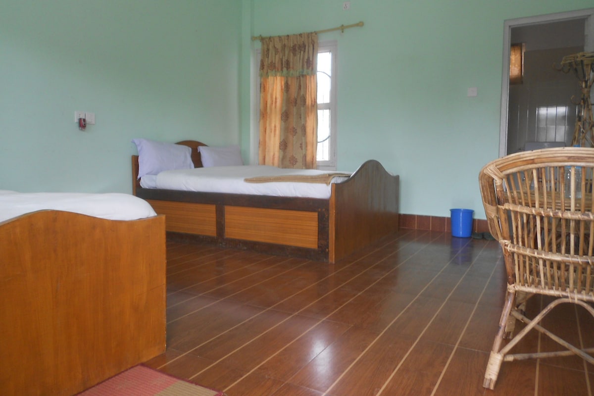 Quarto com cama, uma cadeira e janela com cortinas.