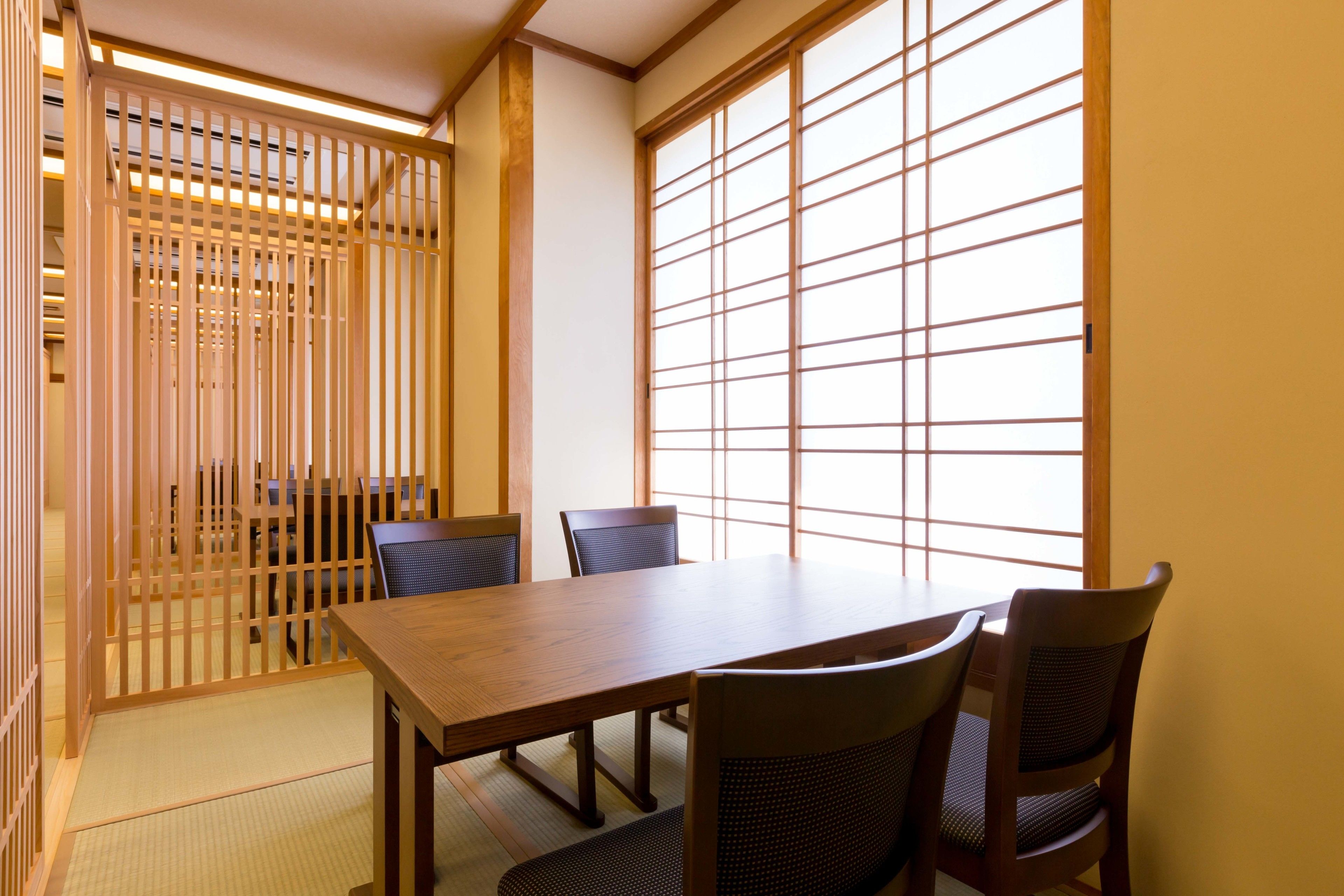 Una habitación tradicional japonesa con suelo de tatami, una mesa de madera baja y puertas correderas shoji.