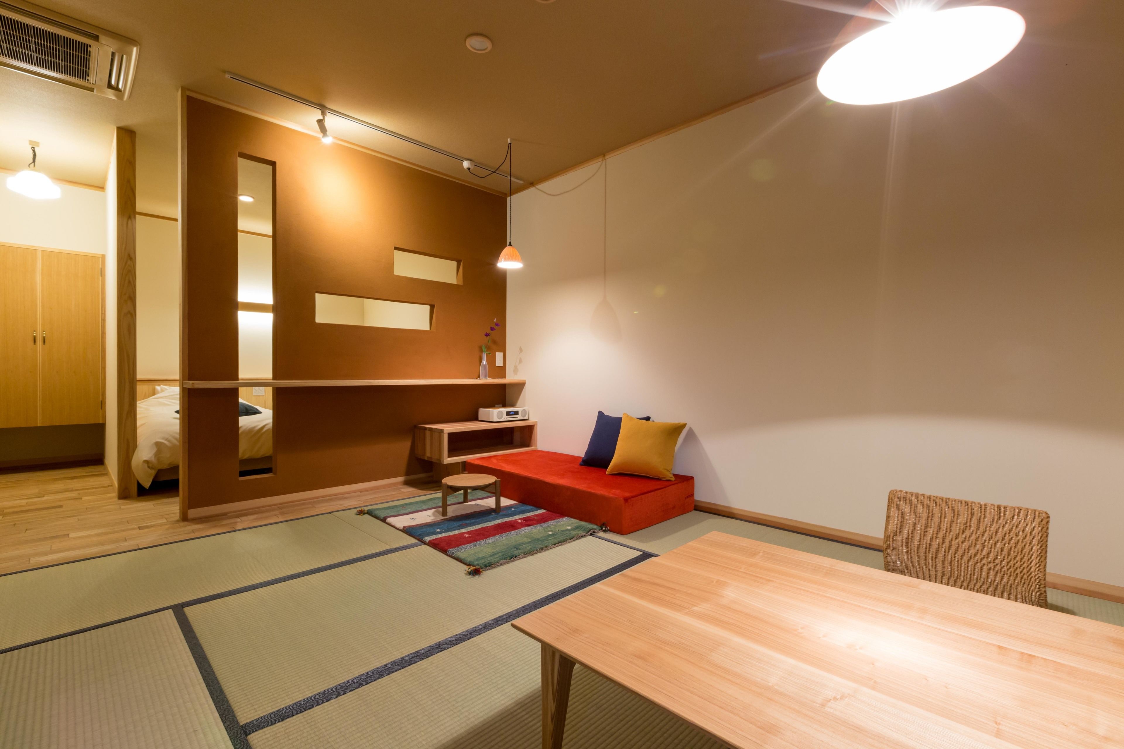 A modern room with a wooden floor, a red sofa, a wooden table, and a chair.