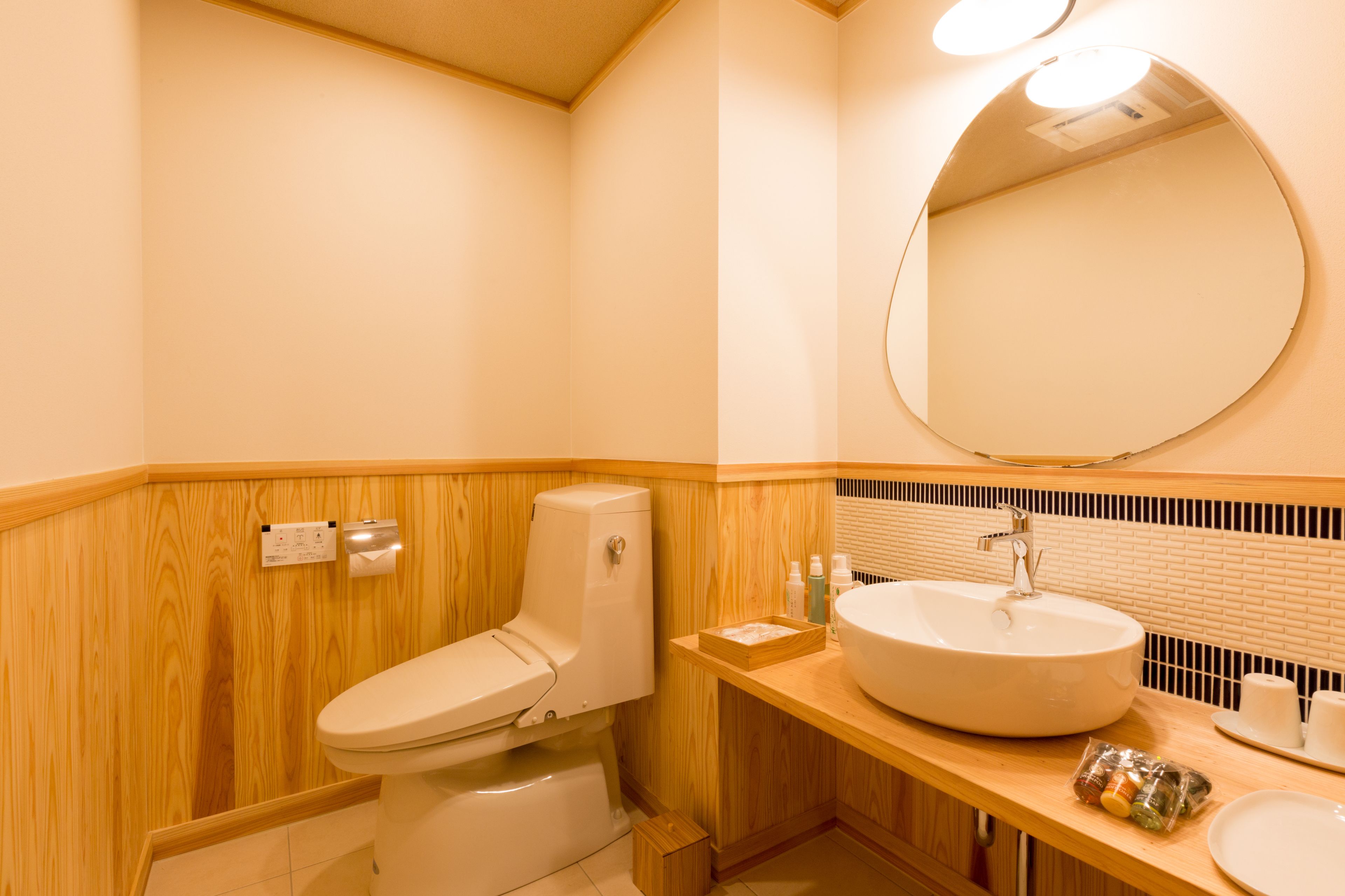 A bathroom with a wooden vanity, a sink, and a toilet.