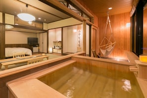 A traditional Japanese onsen with wooden interiors, a hot spring bath, and a hanging swing.