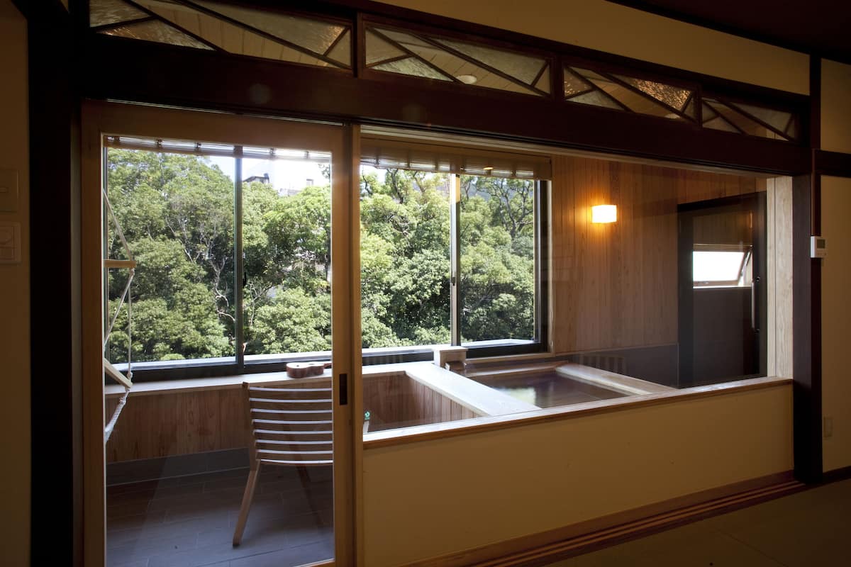A room with large windows, a wooden bench, and a small stool.