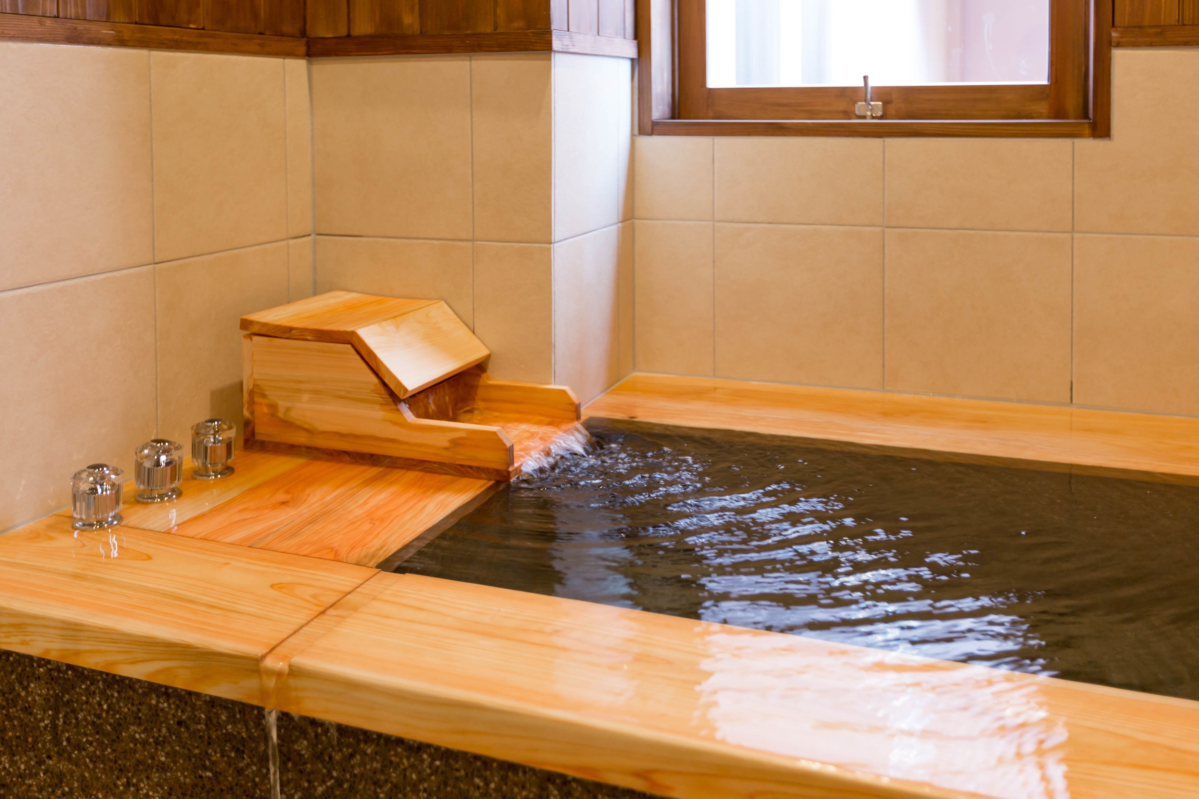 A wooden bathtub with a wooden seat and a small wooden box on the side.