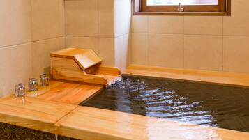 A wooden bathtub with a wooden seat and a small wooden box on the side.