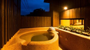 Un jacuzzi en un entorno exterior de madera con una valla de madera y una ventana.