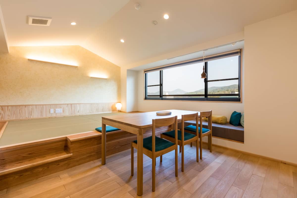 A dining area with a wooden table and chairs, a bench, and a window with a view of the outdoors.