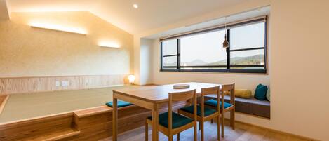 A dining area with a wooden table and chairs, a bench, and a window with a view of the outdoors.