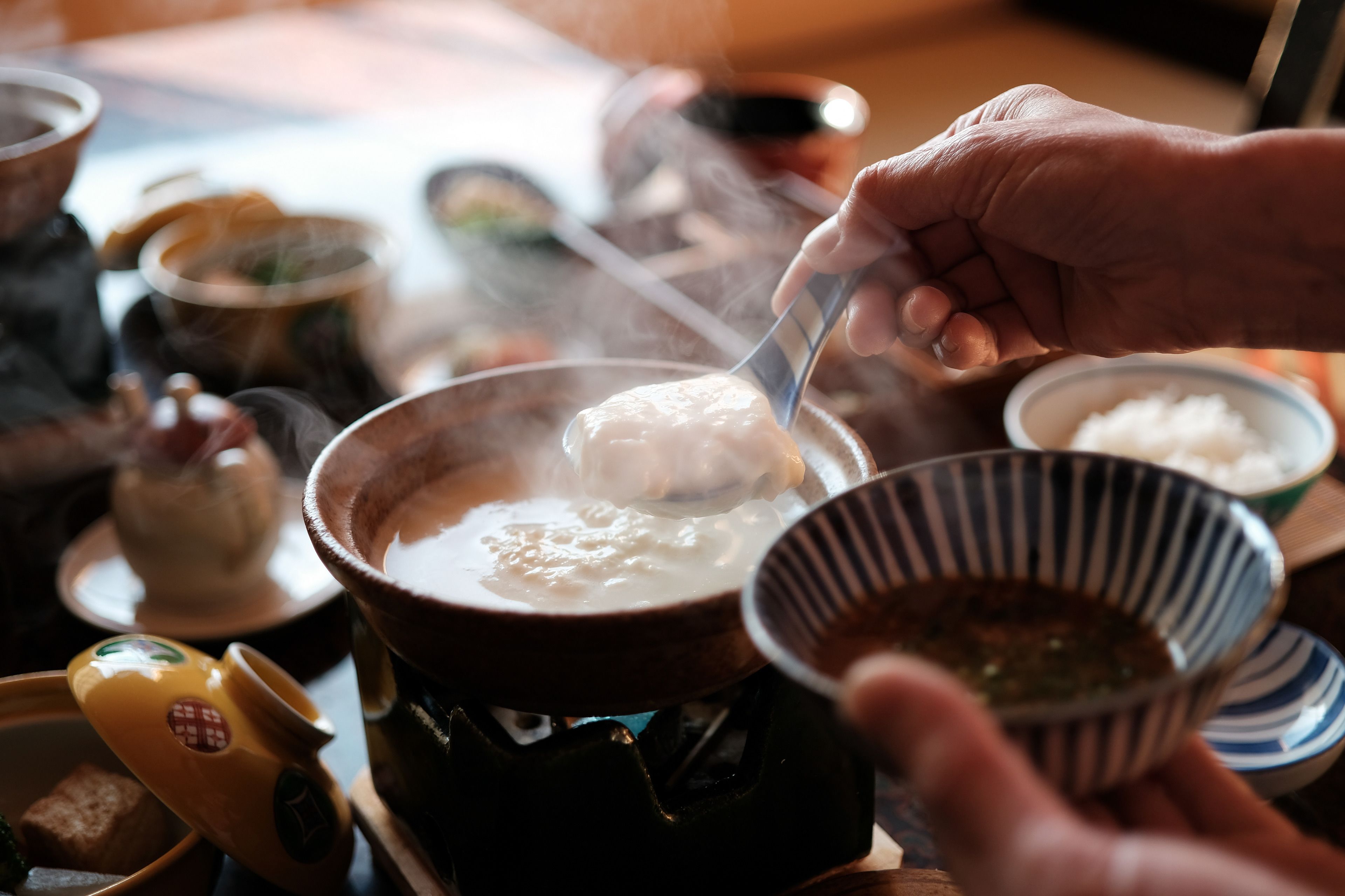 A person serving hot soup from a pot.