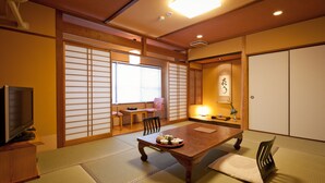 Una habitación japonesa tradicional con suelo de tatami, una mesa de madera baja y un televisor sobre un soporte de madera.