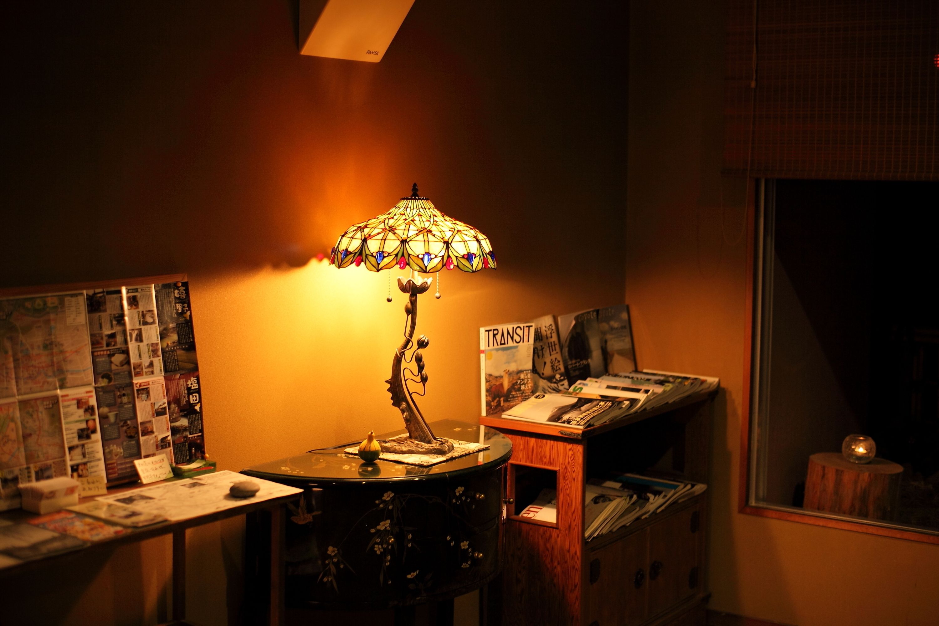 A room with a table lamp, a bulletin board, and a window with a view.