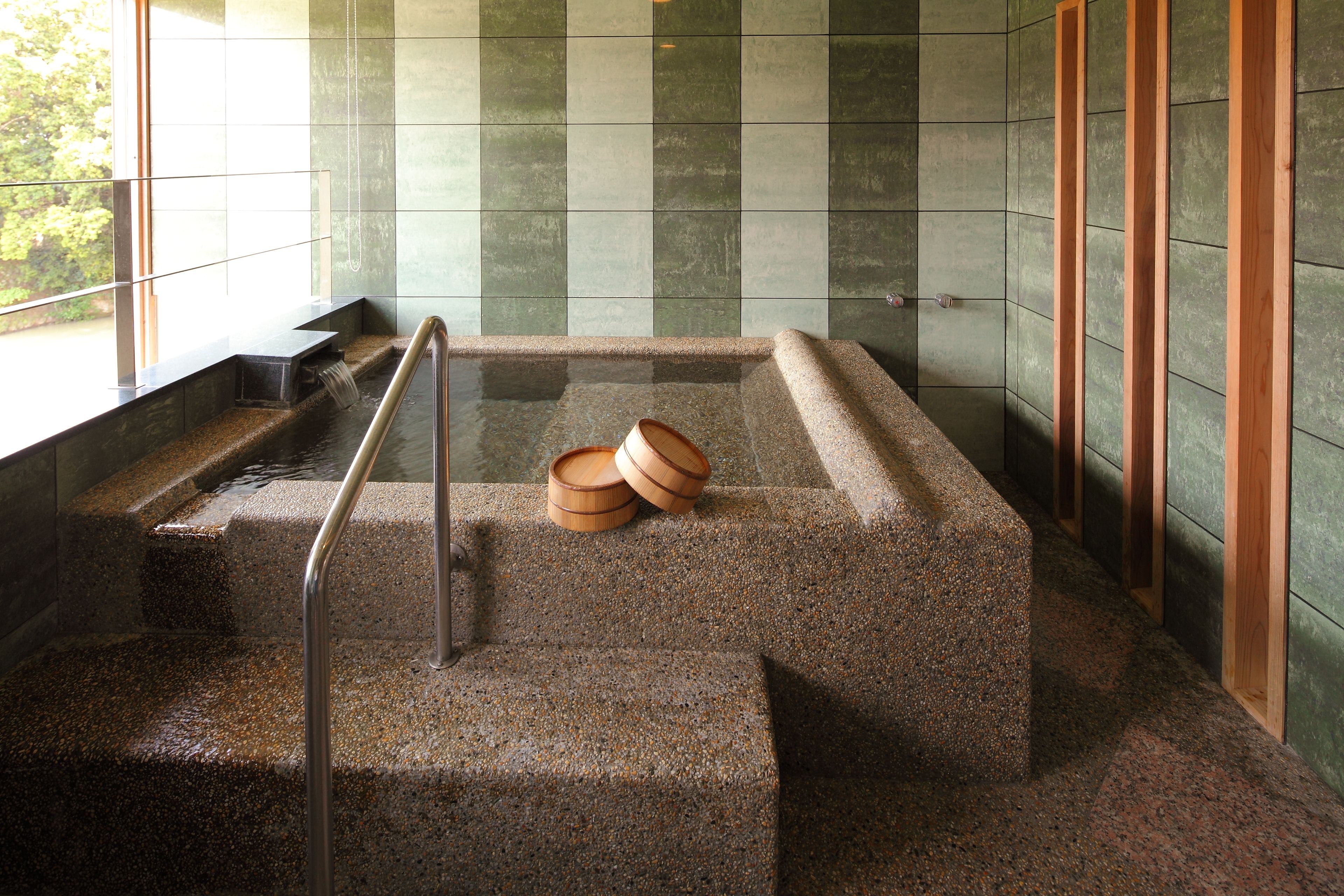 A stone-floored staircase with a wooden handrail and two wooden buckets on the steps.