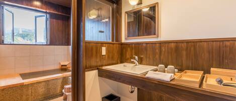 A modern bathroom with a wooden vanity, a large sink, and a bathtub.