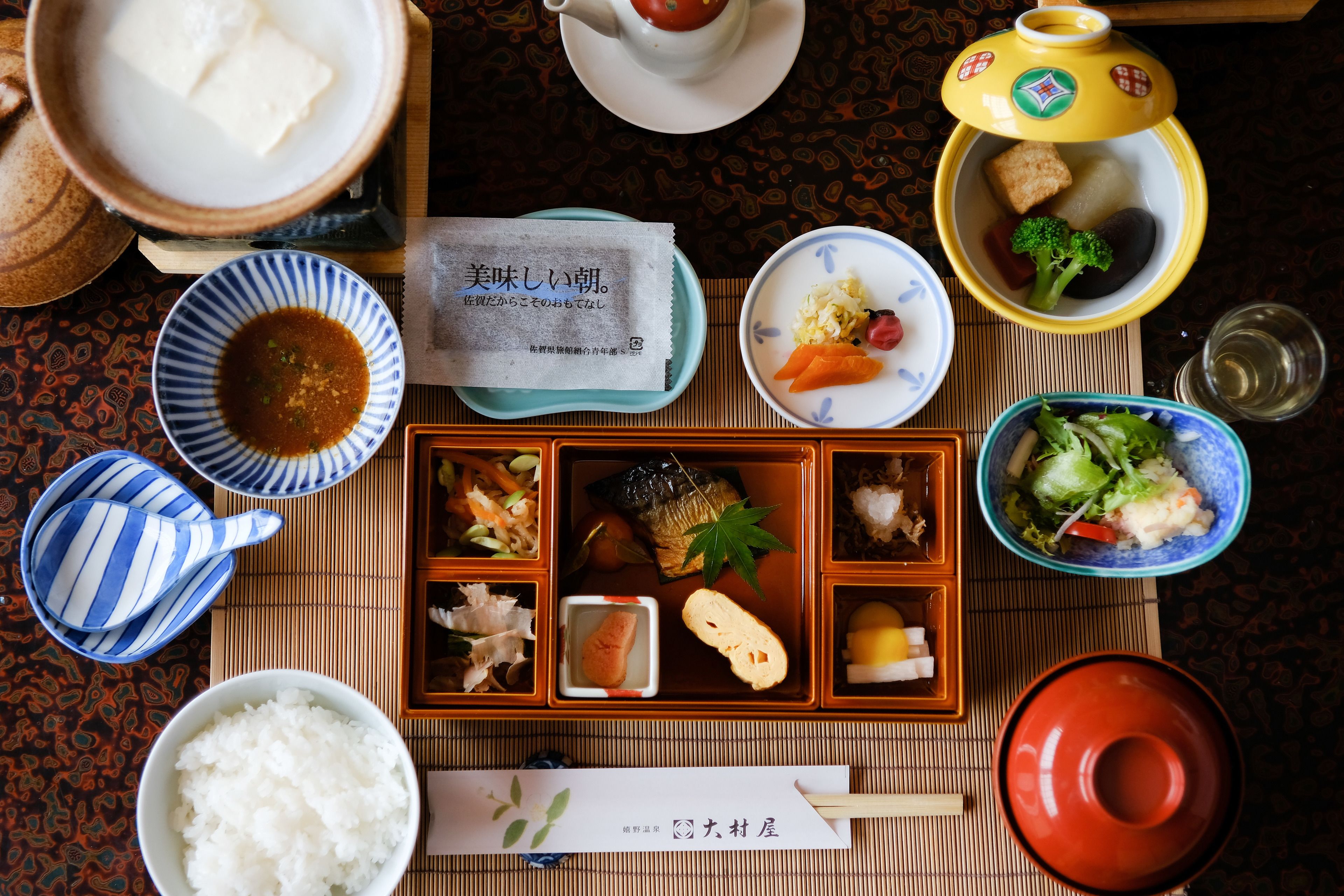 En traditionel japansk måltidsopstilling med flere retter og redskaber.