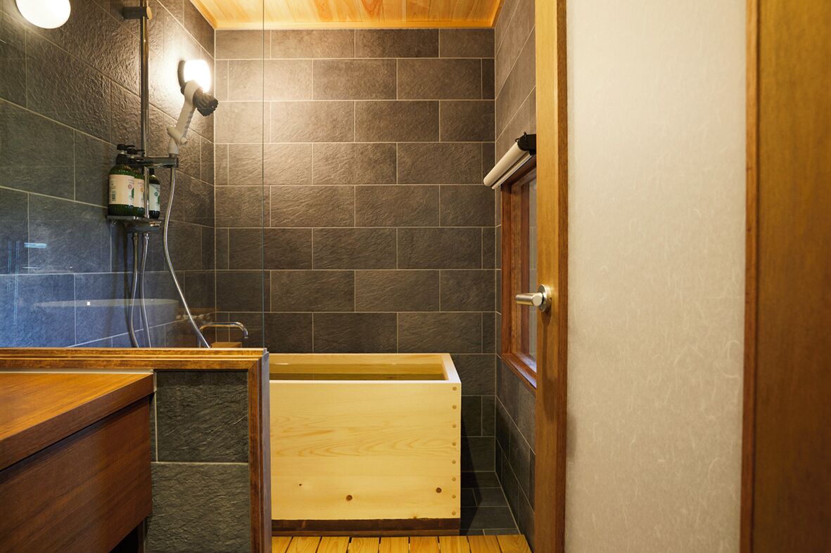 Un baño con ducha, una bañera de madera y un inodoro.
