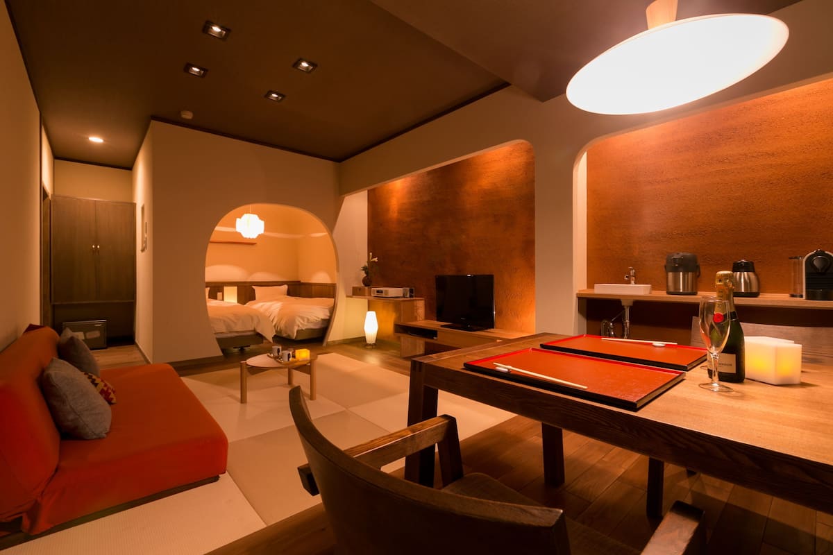 A modern hotel room with a cozy seating area, a dining table, and a kitchenette.