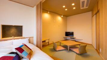 Una habitación de hotel con una cama, televisión, una mesita y esteras de tatami en el suelo.