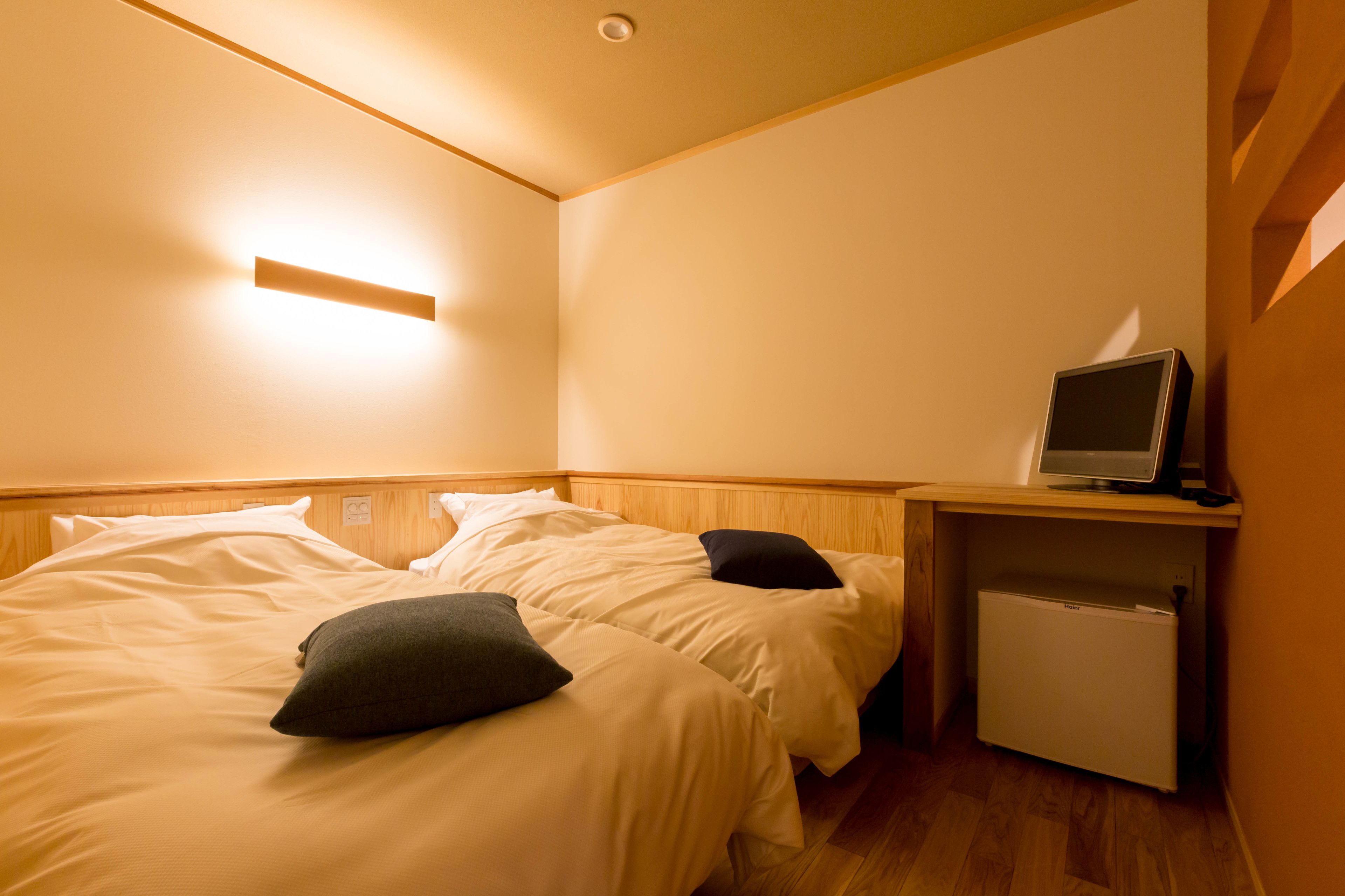 Une chambre d’hôtel avec deux lits, un petit bureau équipé d’un ordinateur et un mini-réfrigérateur.