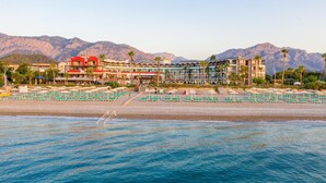 A beachfront hotel with multiple floors, a sandy beach, and mountains in the background. - Armas Labada (Kemer)