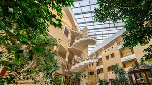 A multi-level atrium with a central spiral staircase, surrounded by greenery and red accents. - Armas Labada (Kemer)