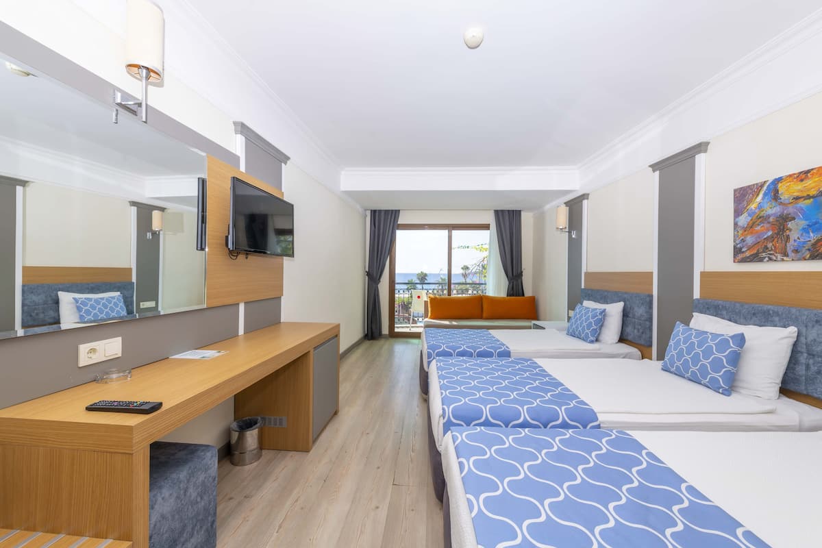Ett hotellrum med en lång säng, ett skrivbord, en tv och utsikt över omgivningarna.