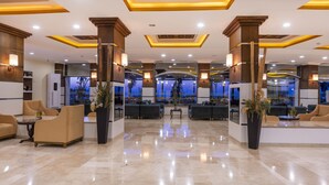 A spacious lobby with modern furnishings, a central seating area, and a view of the cityscape through large windows. - Armas Labada (Kemer)