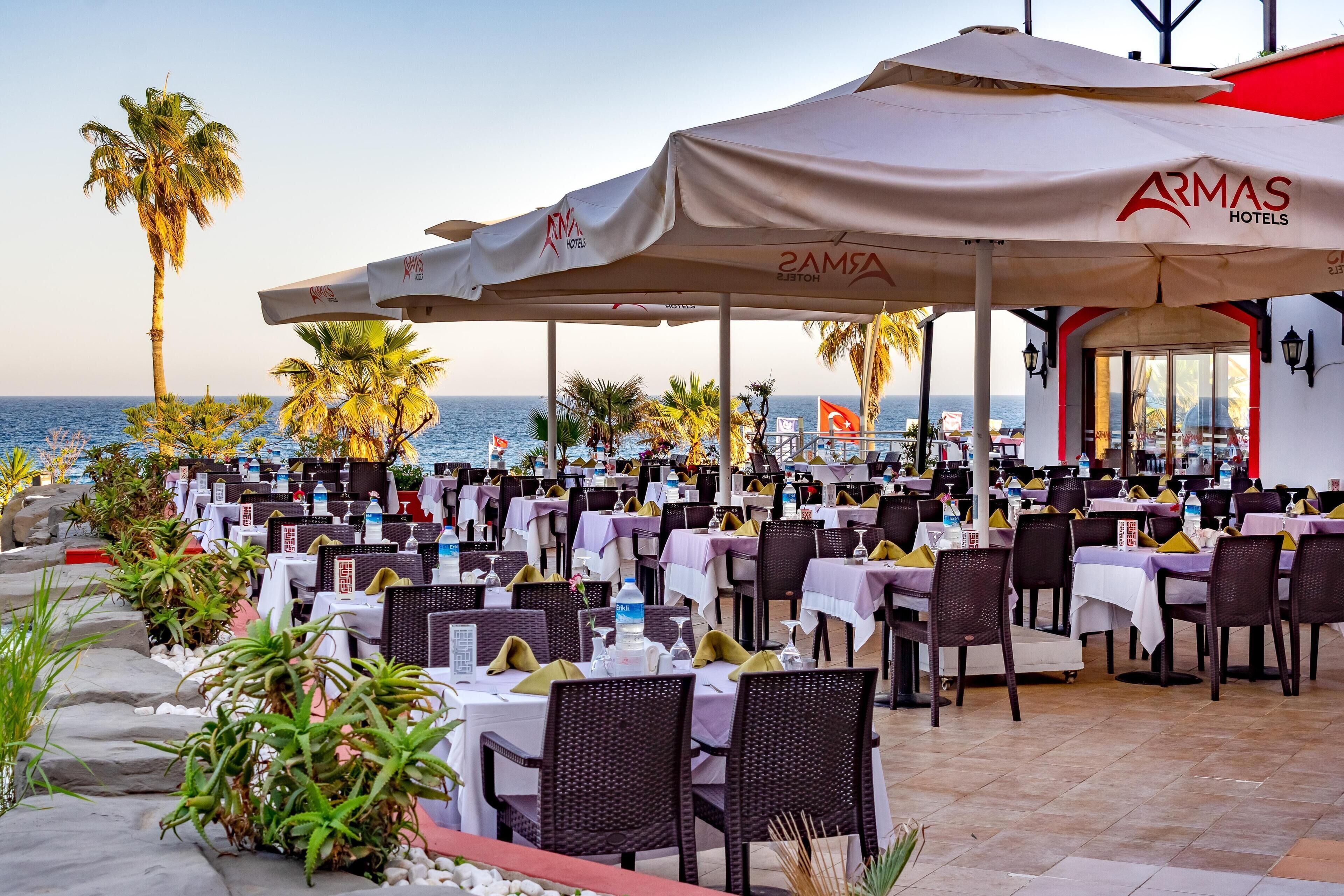 Un restaurante con terraza, mesas con sombrillas y vistas al mar.