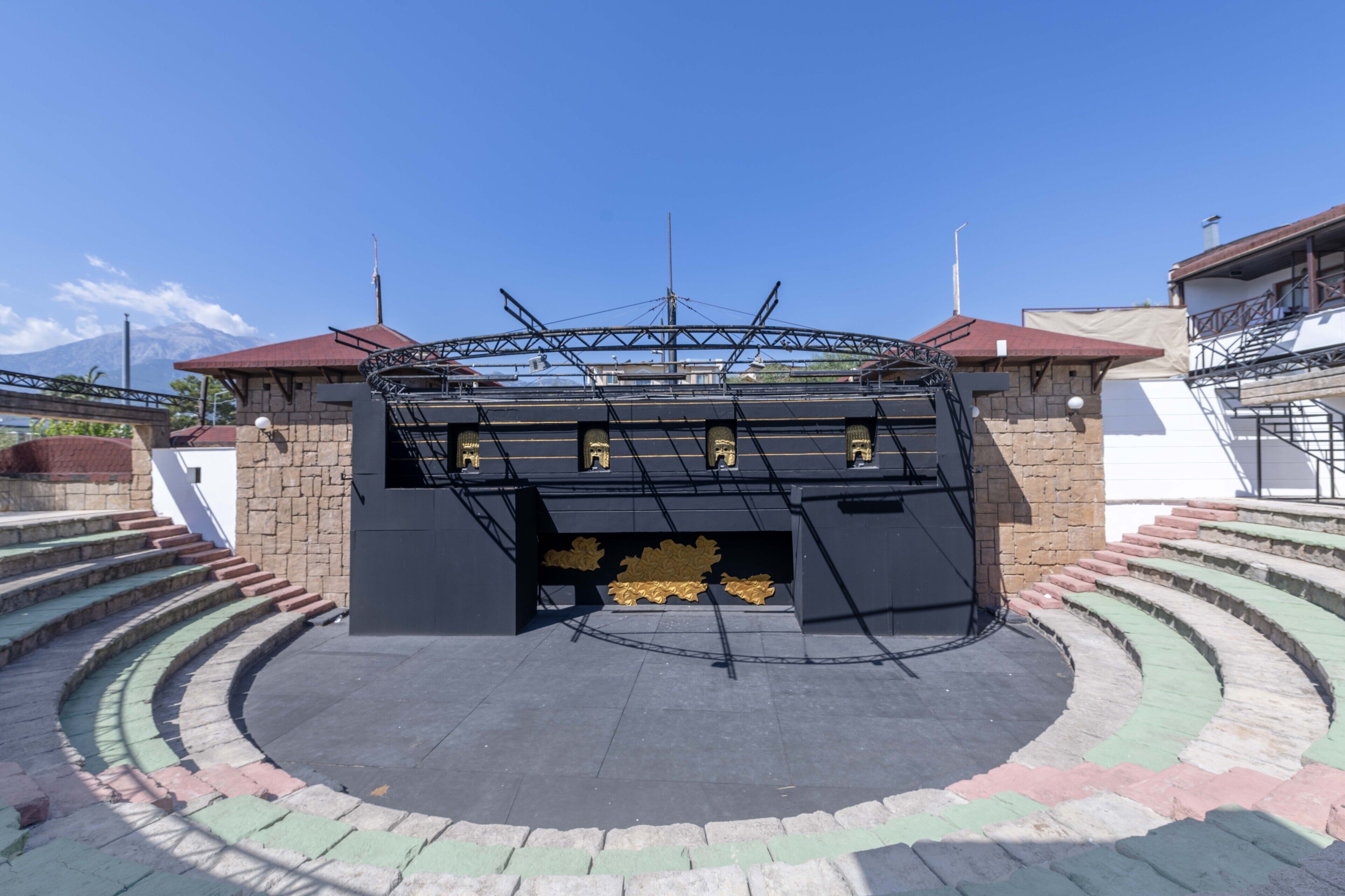 A theater with a circular stage and a stone wall.