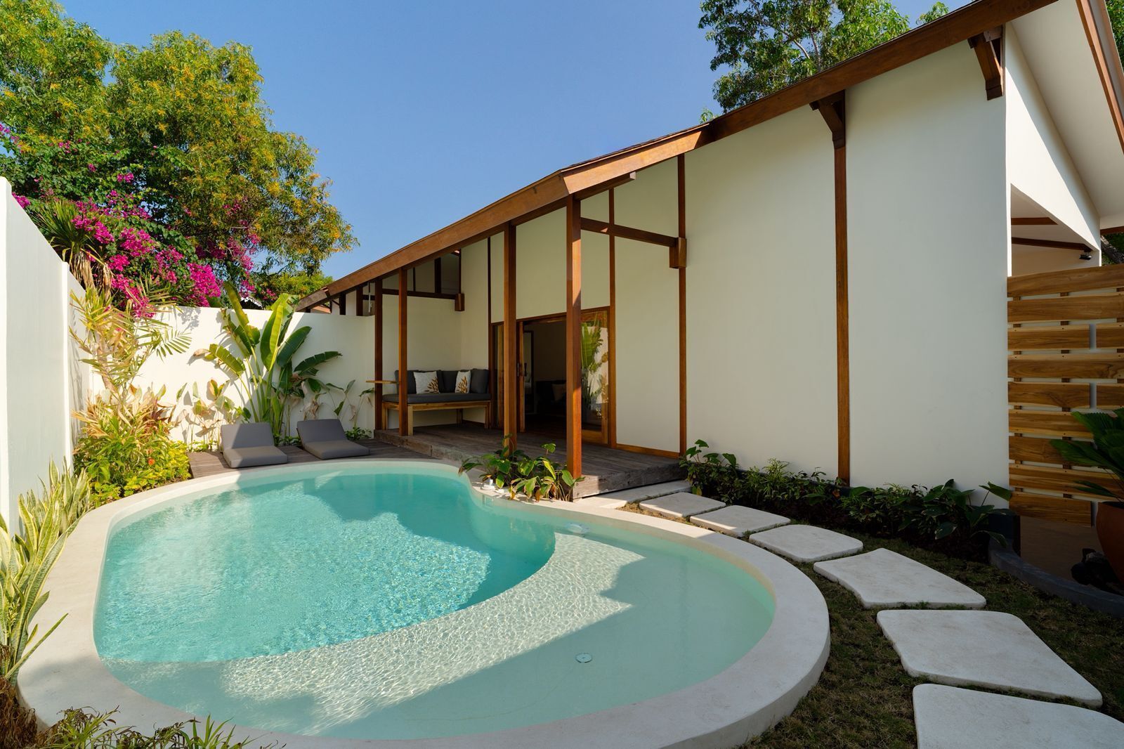A modern outdoor pool area with a built-in seating area and a covered patio.