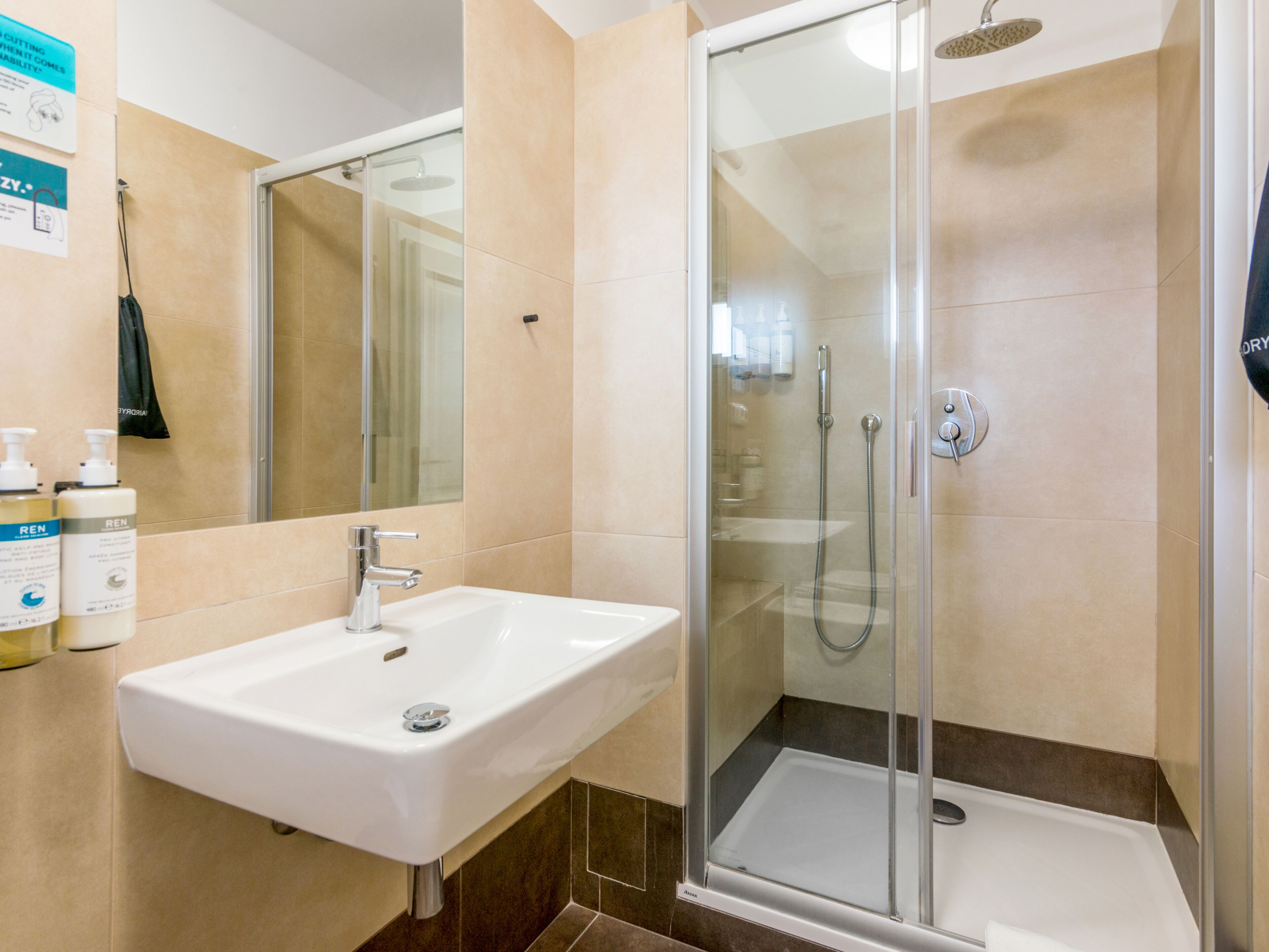 A modern bathroom with a glass-enclosed shower, a white sink, and a mirror.