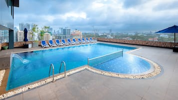 Una piscina al aire libre, sombrillas, sillones reclinables de piscina